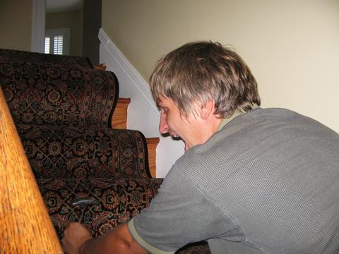 Man fitting a rug to the stairs